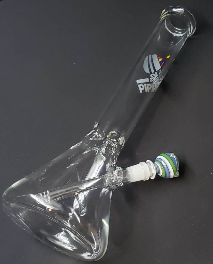 Clear beaker water pipe standing 10 inches tall with a thick 5.5 wide base blue and white swirl bowl adn rocky mountain pipe dreams store branding on the outside of the pipe,